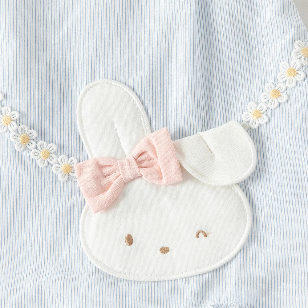 Close-up of bunny appliqué, pink bow and daisy trim on blue dress