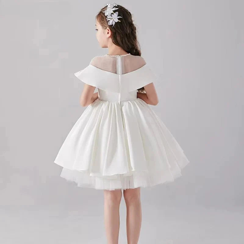 Babelio flower girl in white formal dress with floral hairpiece, studio background